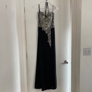 Long bejeweled black prom dress with thin straps and slit up to the thigh.